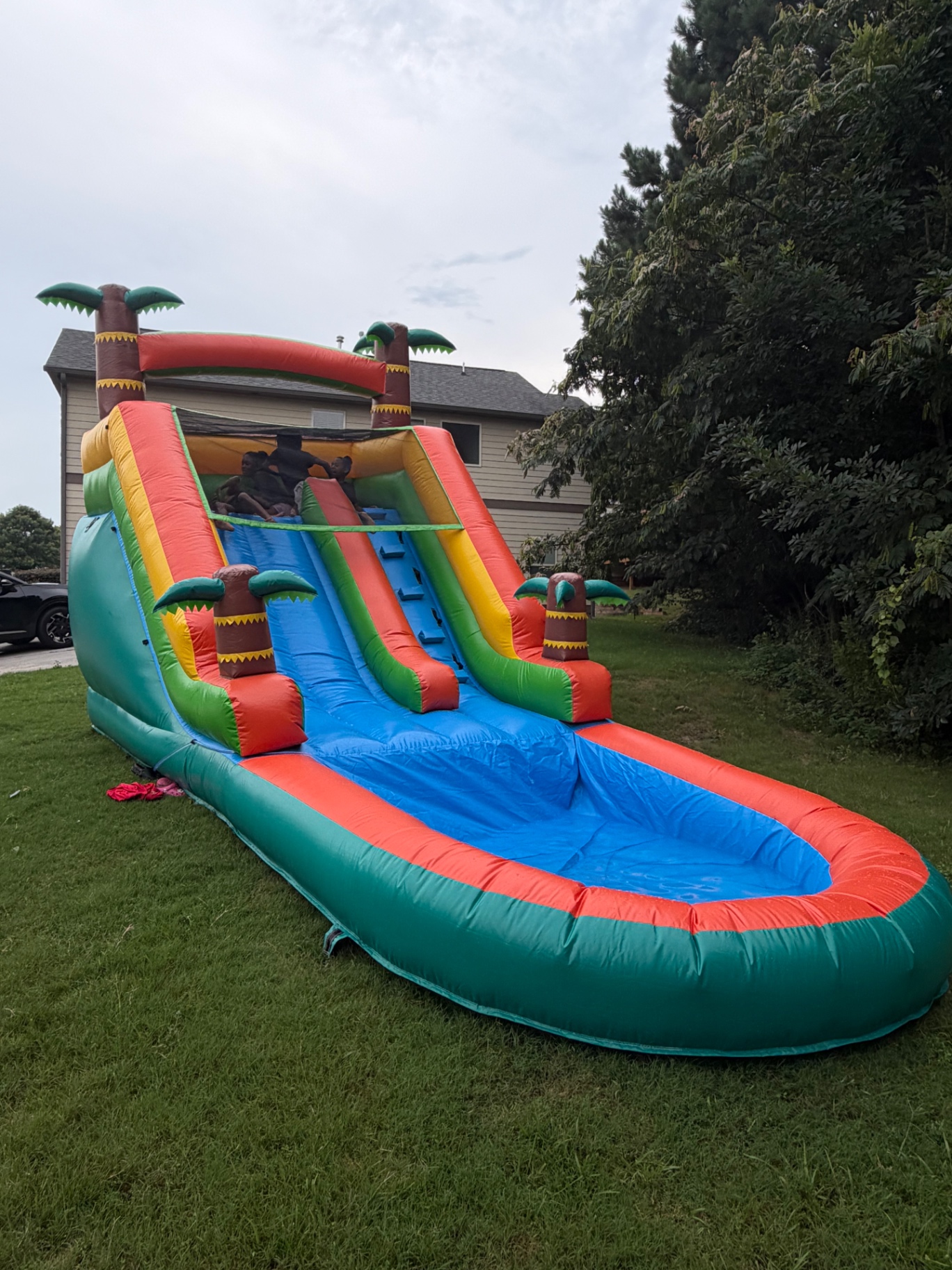 Kids climbing a tropical inflatable water slide with splash pool